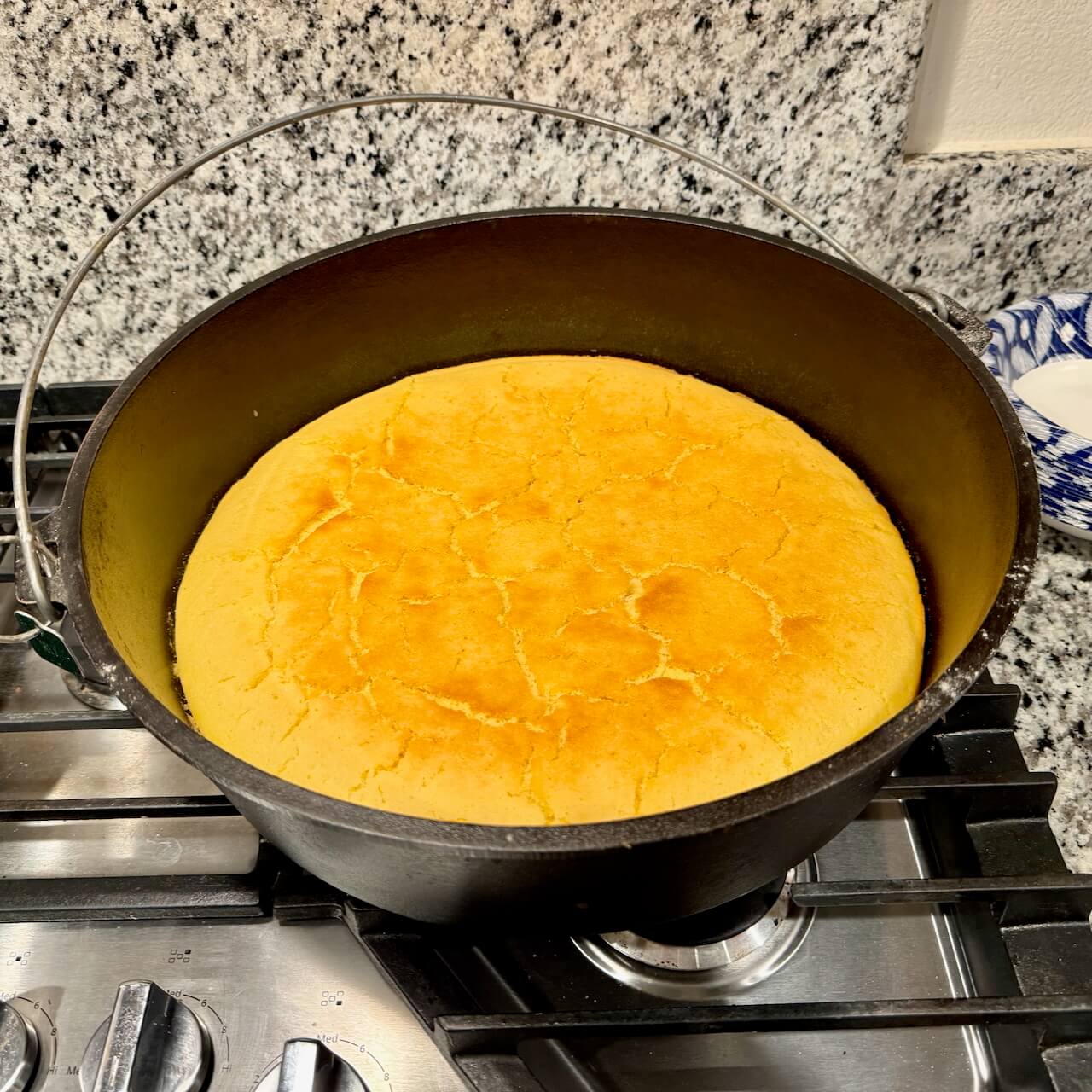A camp Dutch oven filled with golden-brown cornbread, freshly baked and ready to serve.