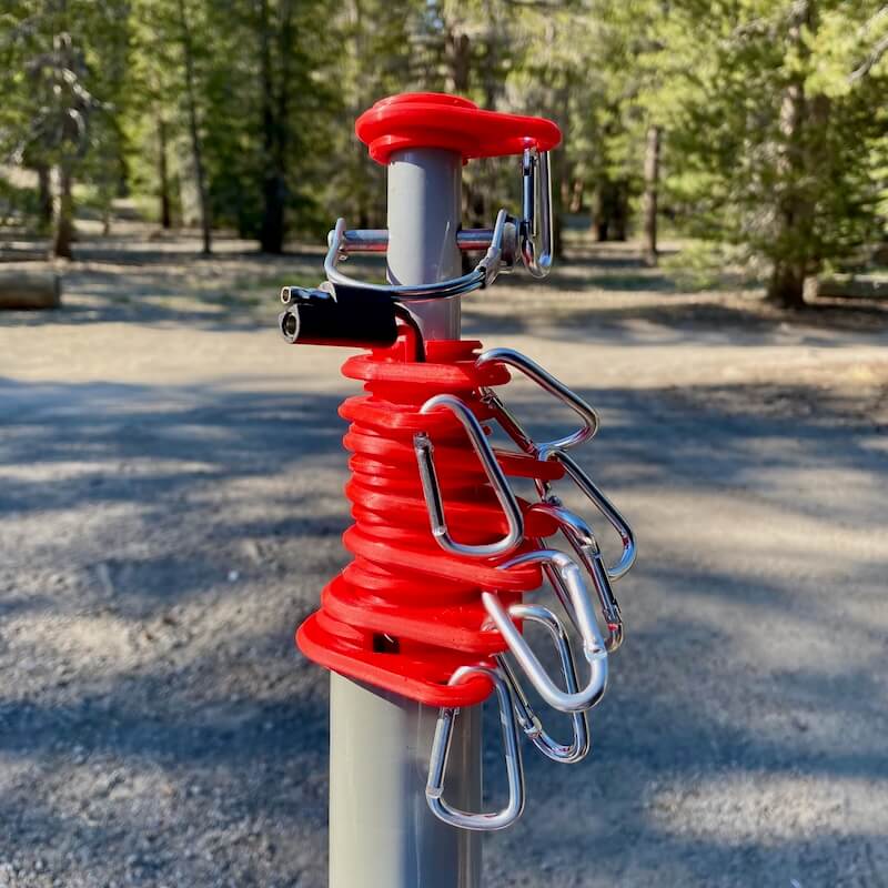 A stack of red flagpole rings and silver carabiner clips on a flagpole, showing an upgraded set with enough rings to fly four flags.