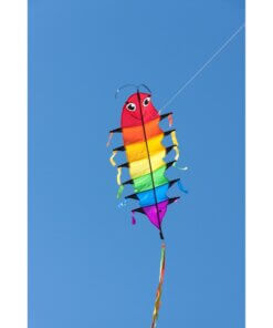 The HQ Flapping Willie Worm kite, brightly colored, flying high in a clear blue sky, showing its friendly face.