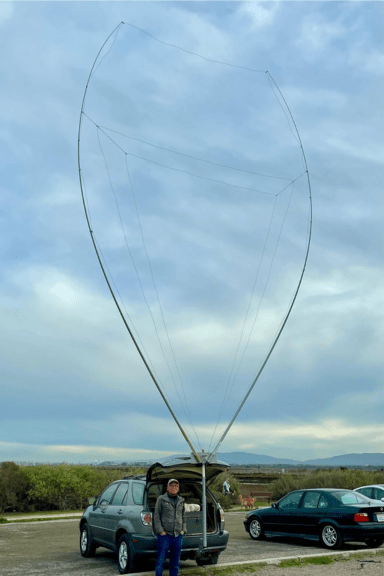 A wide-angle view of the fully assembled portable 4-band delta loop antenna, showing its impressive height and shape when mounted on a vehicle.