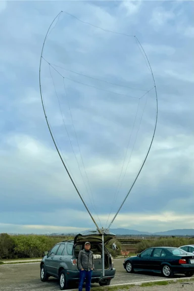 A wide-angle view of the fully assembled portable 4-band delta loop antenna, showing its impressive height and shape when mounted on a vehicle.