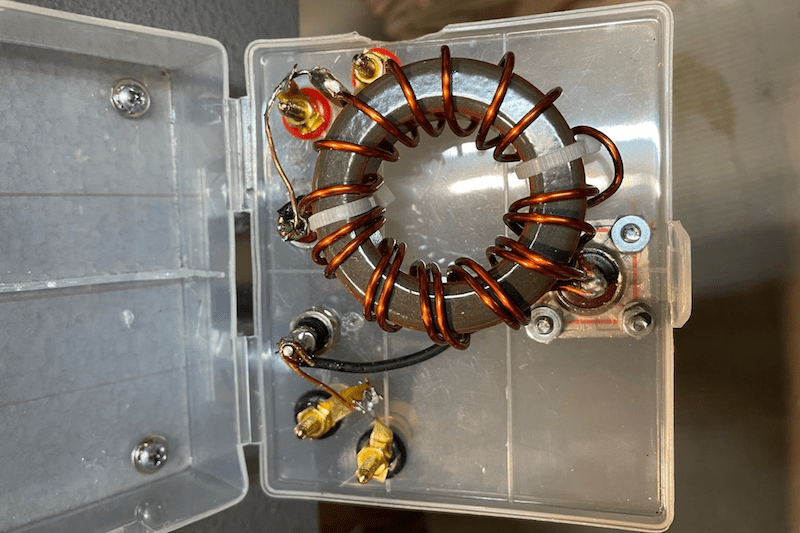 A detailed close-up of the internal wiring of the 2:1 balun, showing the enameled copper wire wrapped around the toroid core.