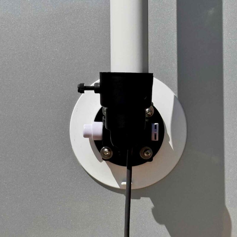A straight-on close-up of the RV Flag Pole Buddy Suction Cup Mount 2.0 showing the vacuum plunger, pole thumbscrew, and a black cable running from the pole.