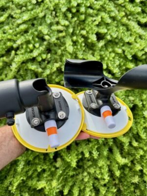 A hand holding the complete RV Flag Pole Buddy Suction Cup Mount 2.0 kit, showing both the upper "TWIST" mount and the lower "CUP" mount.