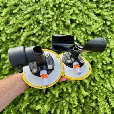 A hand holding the complete RV Flag Pole Buddy Suction Cup Mount 2.0 kit, showing both the upper "TWIST" mount and the lower "CUP" mount.