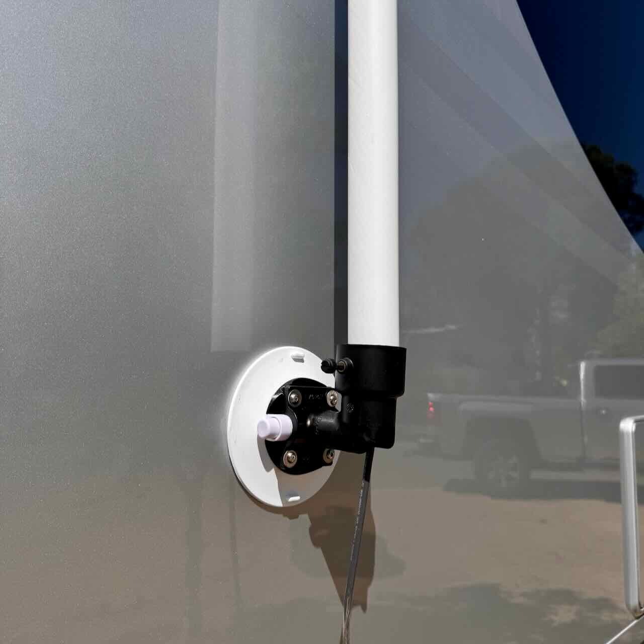 Close-up of the lower RV Flag Pole Buddy Suction Cup Mount 2.0 installed on the side of a silver RV, holding a white pole.