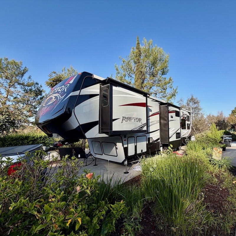 A luxury Keystone Raptor fifth wheel demonstrating a professional Starlink RV setup for resorts in a lush, wooded environment.